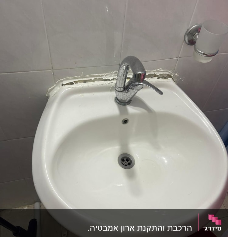 כיור עם ברז ותיקון איטום בקיר